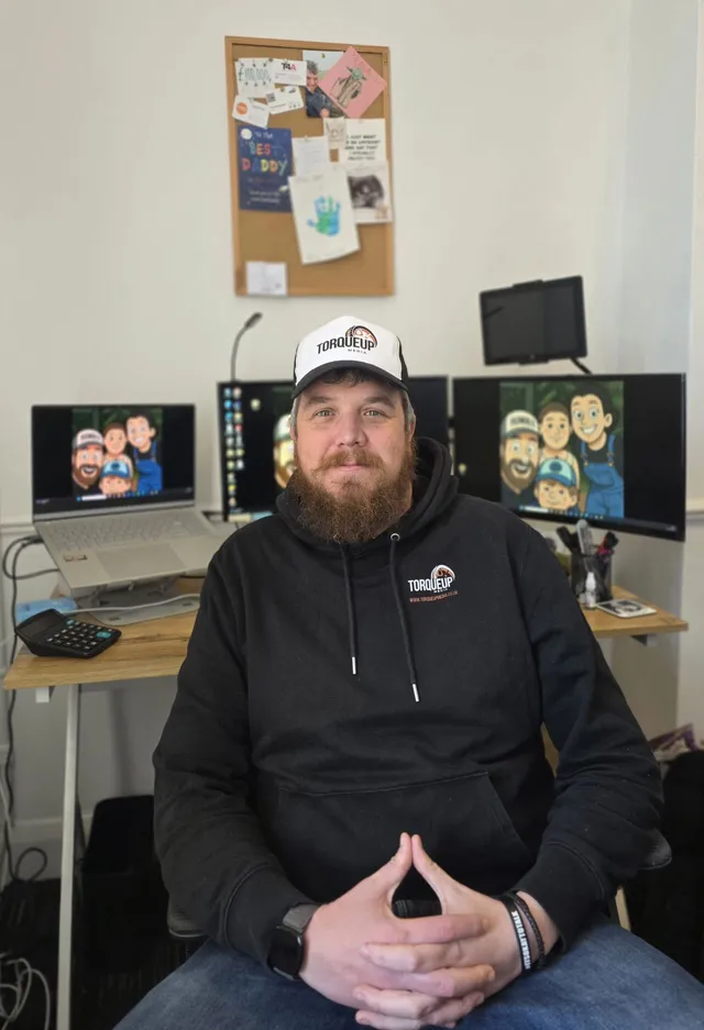 Andy Billingham, founder of TorqueUp Media, at his desk in TorqueUp branded workwear